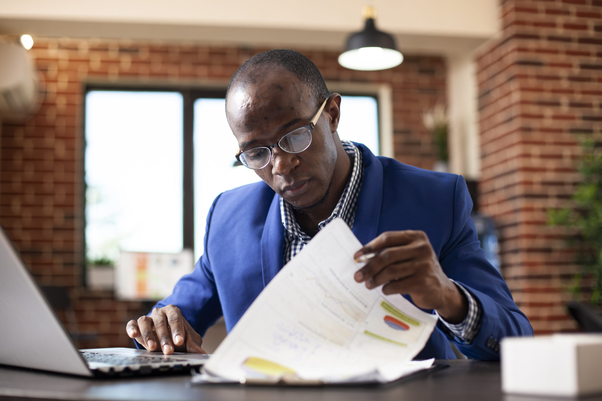 Person applying for a government grant online using laptop and official forms